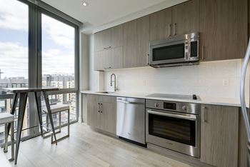 A modern kitchen with stainless steel appliances and a large window overlooking the city.at Elysium Fourteen, Washington, DC 20009